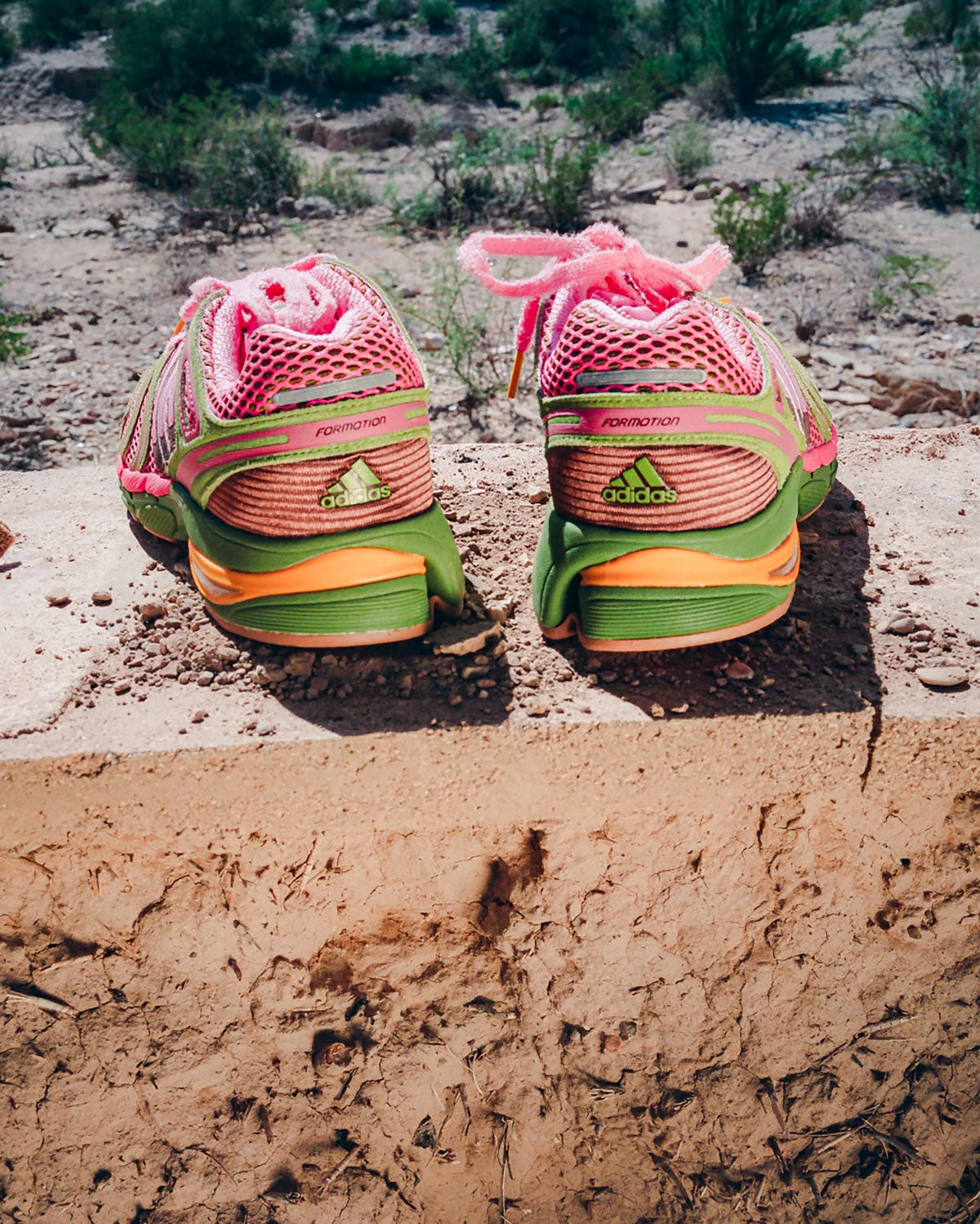 The Tipping Point x adidas Adistar Control 5 in pink and green, heel view in the Texas desert. Photo via Sneaker News