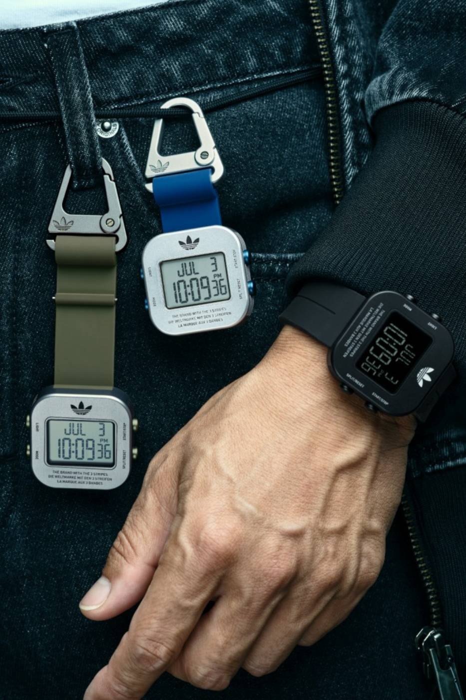 adidas Originals ADAPTIK ONE carabiner watch worn on the wrist and clipped to a bag. Image via adidas Originals / Hypebeast