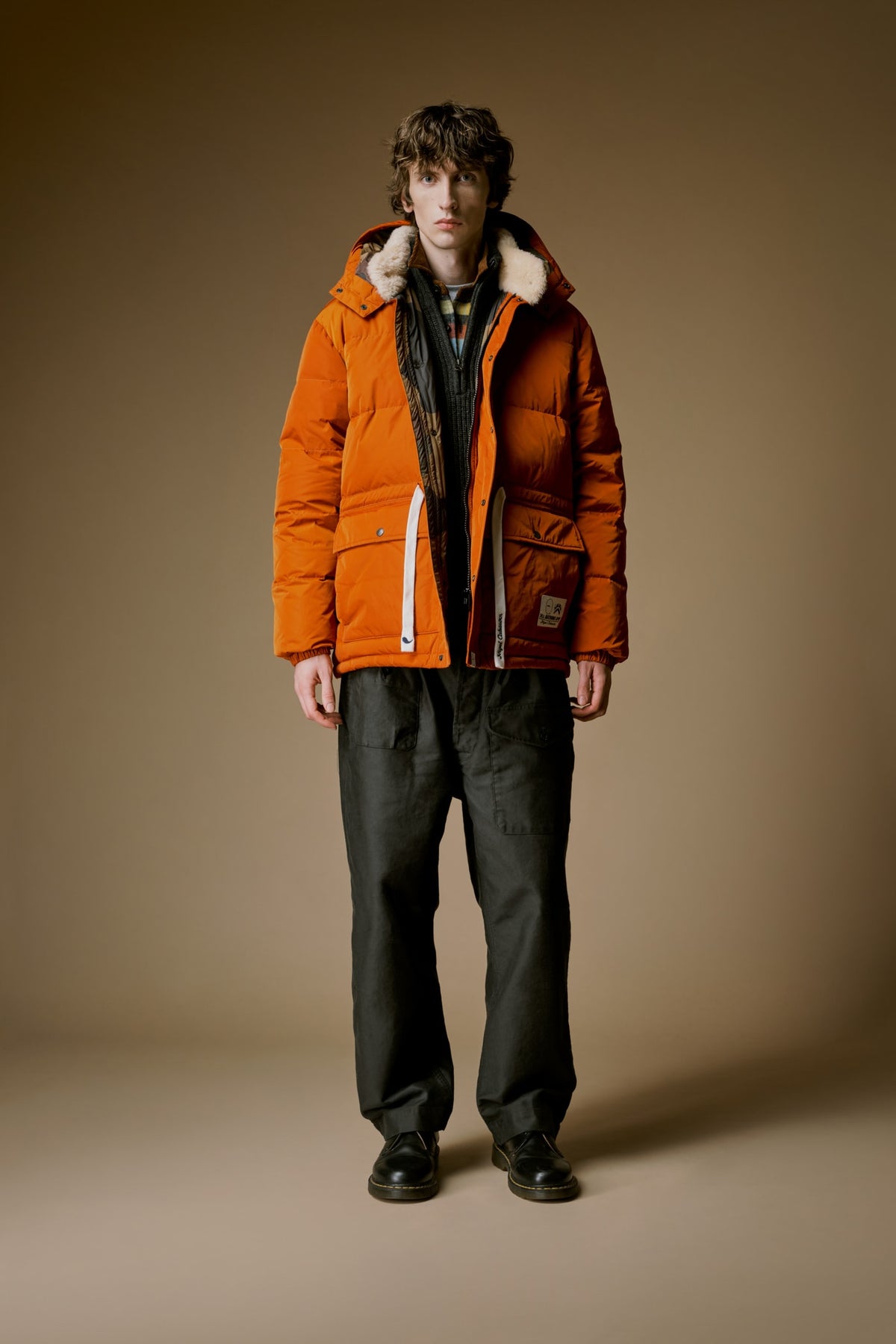 MR. BATHING APE x Nigel Cabourn FW26 lookbook, orange down jacket. Image via MR. BATHING APE / Nigel Cabourn and Hypebeast Japan