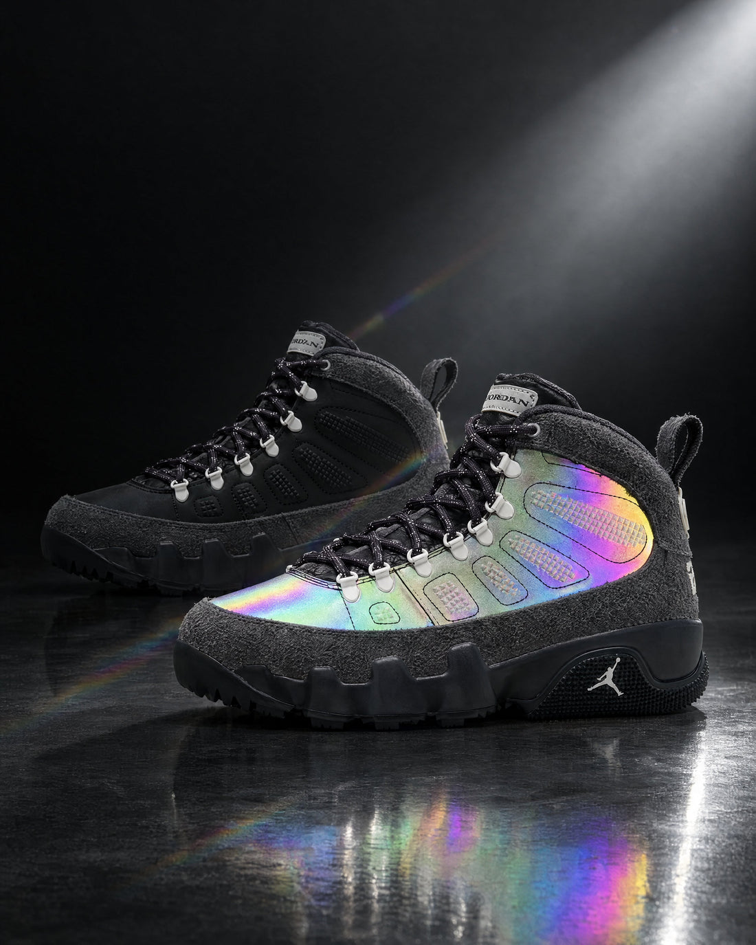 Air Jordan 9 Retro Boot NRG Iridescent in Anthracite/Multi-Color — pair on a dark reflective floor under a spotlight, photo by ONENESS