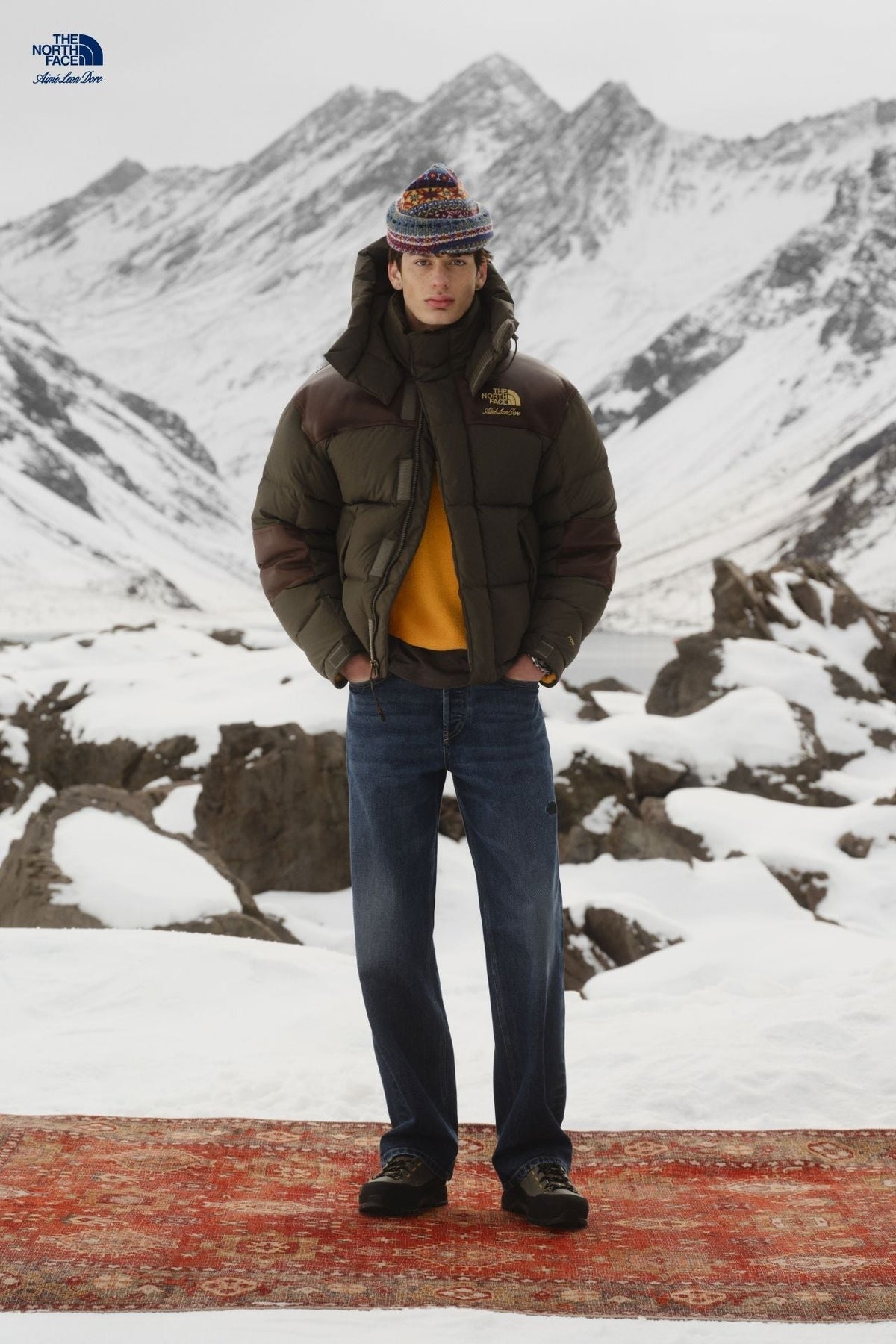 Aimé Leon Dore × The North Face FW26 campaign — model in olive collab puffer on mountain rug