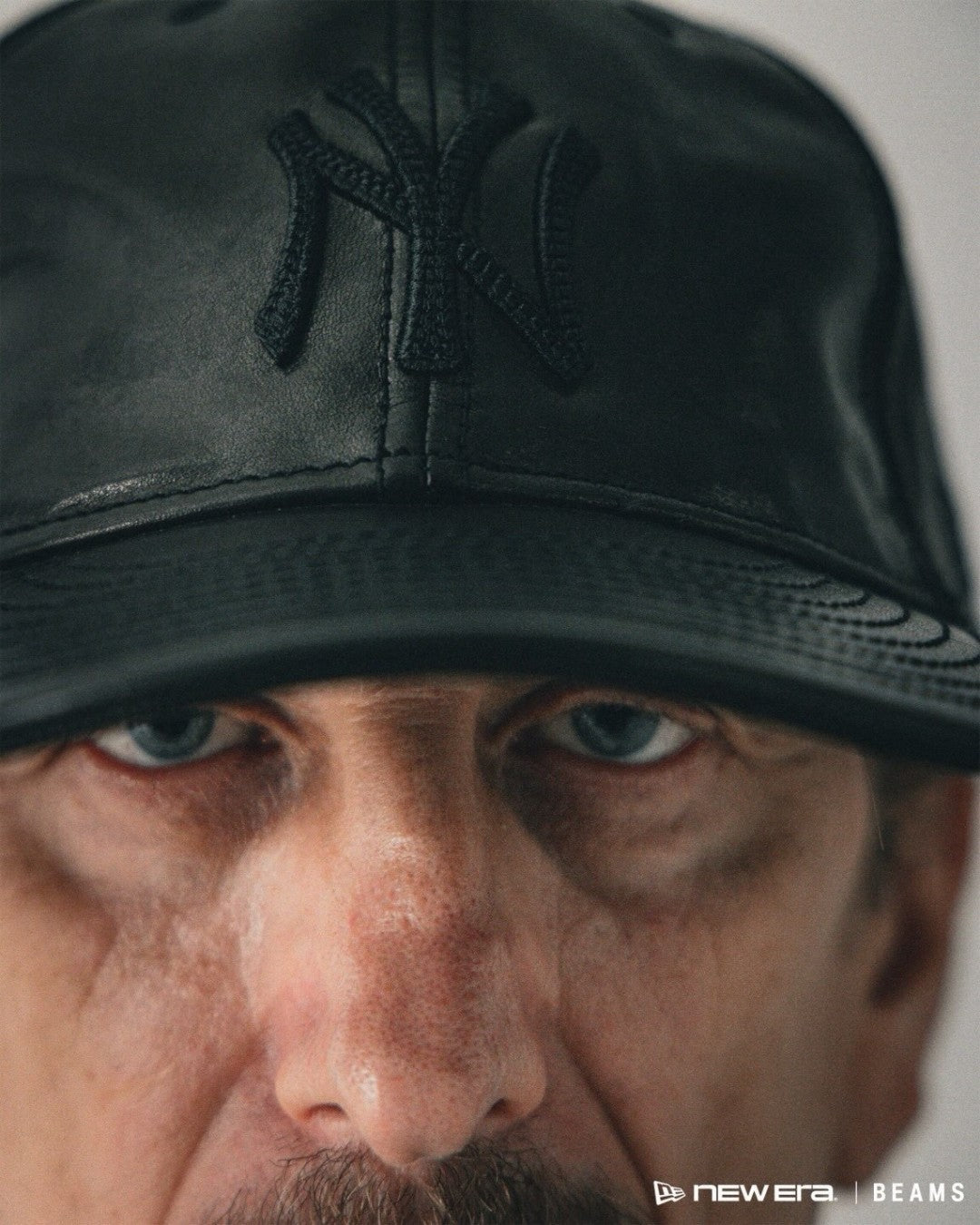 BEAMS × New Era PC 9FIFTY leather cap campaign — black leather NY logo on-model close-up
