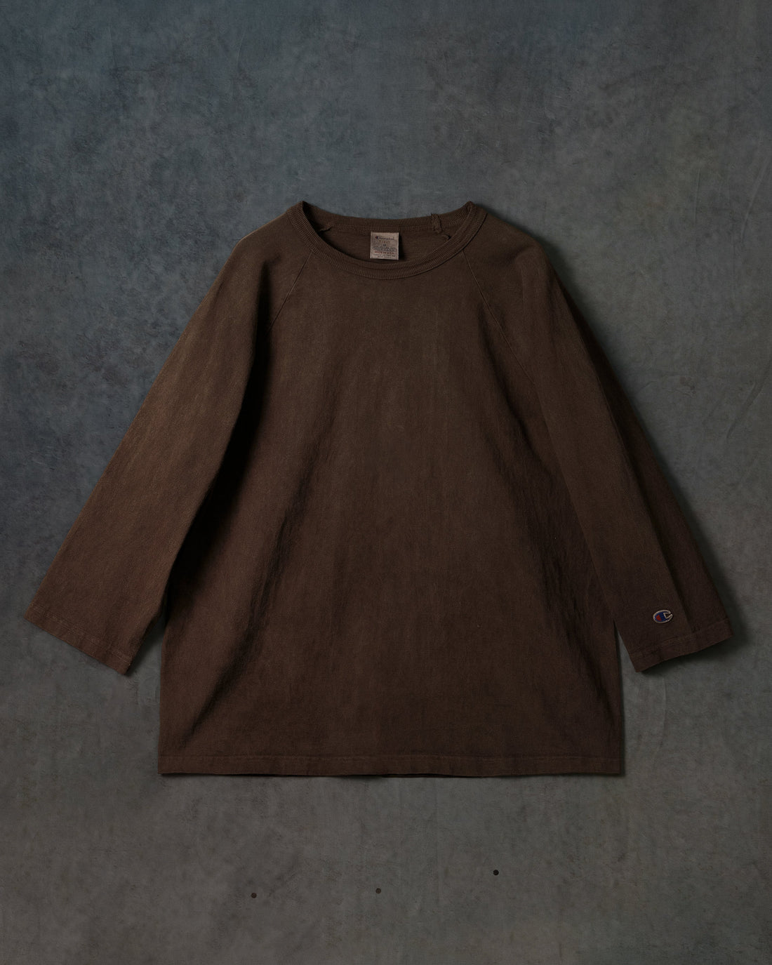 Champion Made in USA T1011 AMAMI DOROZOME long sleeve — mud-dyed dark brown flat on textured press backdrop — official Champion Japan