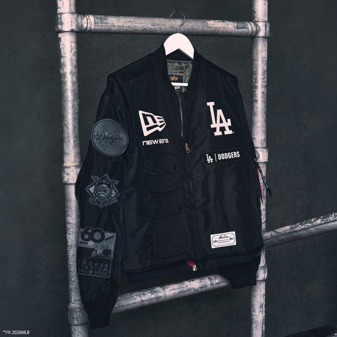 New Era × Alpha Industries MLB Dodgers MA-1 bomber on industrial hang — courtesy New Era Japan